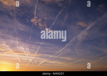 Des traînées de vapeur de l'avion au lever du soleil, en traversant le vaste ciel de Lincolnshire, Royaume-Uni. Banque D'Images