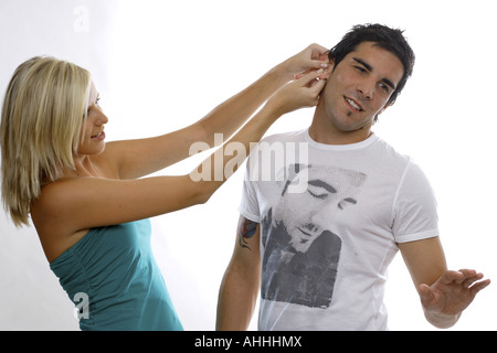 Jeune femme tirant l'oreille d'un jeune homme Banque D'Images