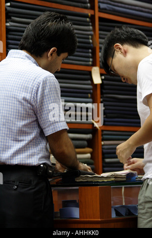 Tailleur de Hong Kong et d'un matériau de récupération des clients en face de Reems de tissu Costume Banque D'Images