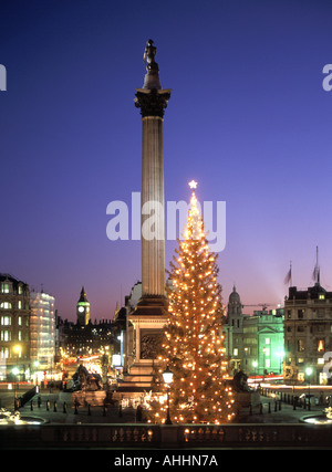 Scène de DUSK SKY Trafalgar Square avec lumières et décorations sur l'arbre de Noël colonne de Nelsons Big Ben extrémité distante de Whitehall emblématique Londres Angleterre Royaume-Uni Banque D'Images