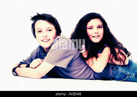Boy laying on floor with girl sur son dos les deux smiling at camera Fond blanc Fond blanc Banque D'Images