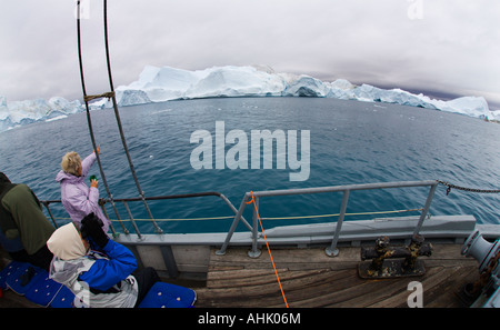 Dame de l'ultra grand angle et les visiteurs faisant remarquer d'énormes icebergs du rail de petit bateau à Ilulissat, sur la côte ouest du Groenland Banque D'Images