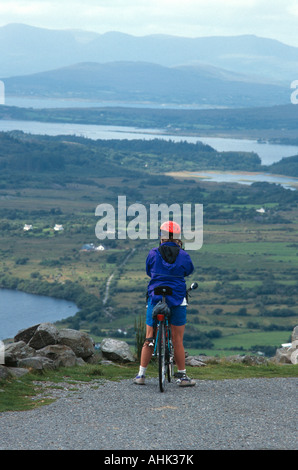 Femme avec location debout sur le côté de la route de Col Healy regardant le paysage dans le comté de Cork en Irlande Banque D'Images