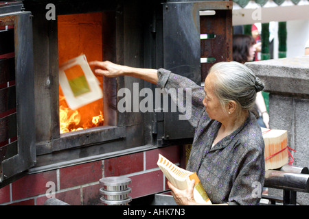 Personnes âgées femme chinoise Burning faux argent pour honorer les ancêtres morts, Temple Man Mo, Hong Kong, Chine Banque D'Images