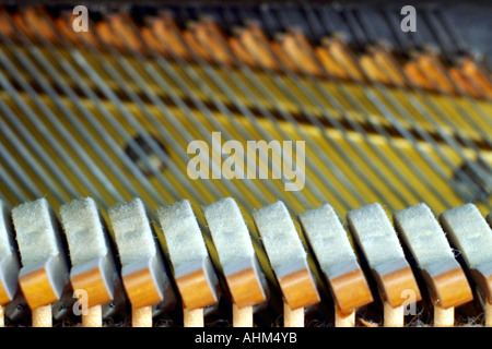 Feutre-maillets couverts à l'intérieur d'une caisse de résonance du piano, avec des cordes d'acier et d'harmonie dans l'arrière-plan Banque D'Images