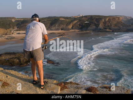 Pescador en los acantilados de la plage de Zambujeira do Mar al atardecer Banque D'Images