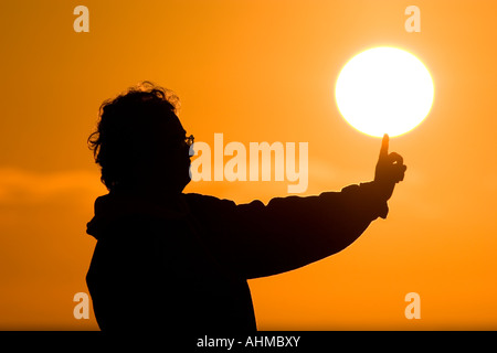 Femme d'âge moyen de toucher le soleil du matin avec son doigt. Banque D'Images