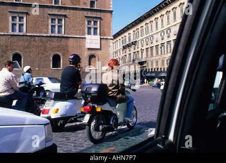 Les personnes sur les motos, les scooters, les cyclomoteurs et les Vespas dans la circulation de midi vu de l'intérieur de la voiture.Scène de rue italienne.Rome, Italie Banque D'Images