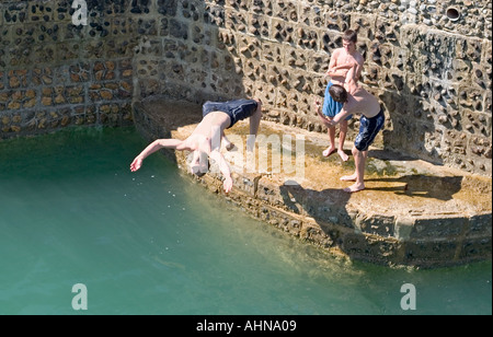 Adolescents sautant épi dans la mer. Brighton, Angleterre Banque D'Images