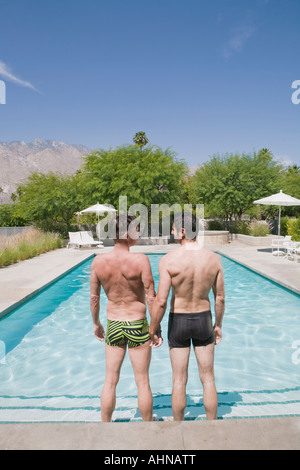 Gay couple standing in swimming pool Banque D'Images