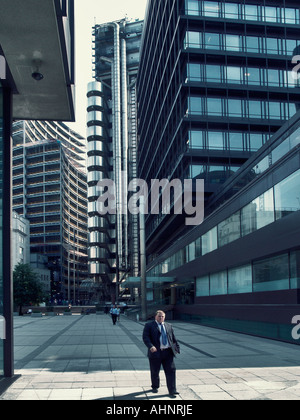 Personne d'affaires marcher dans la ville avec la Lloyds building à l'arrière-plan, la ville de Londres, Angleterre Banque D'Images