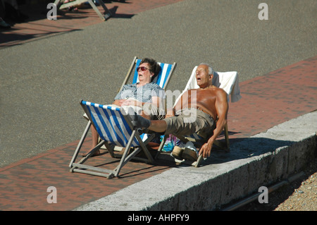 Vue horizontale surélevée comique d'un couple de personnes âgées endormi la bouche ouverte en transats bénéficiant du soleil Banque D'Images