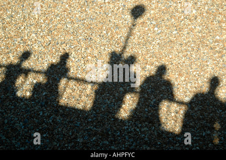 Close up horizontale d'ombres projetées sur les galets d'un groupe de personnes debout sur la promenade. Banque D'Images
