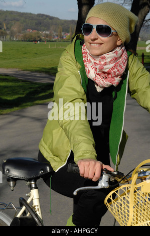 Fille sur un vélo dans une gaine verte Banque D'Images