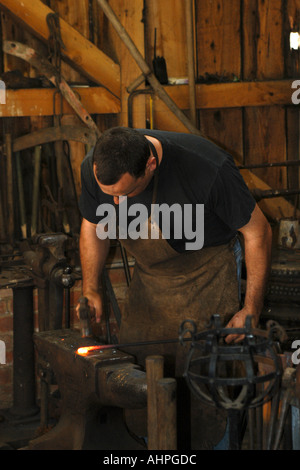 Un forgeron au travail dans sa forge la création d'un ensemble de portes en fer forgé Banque D'Images