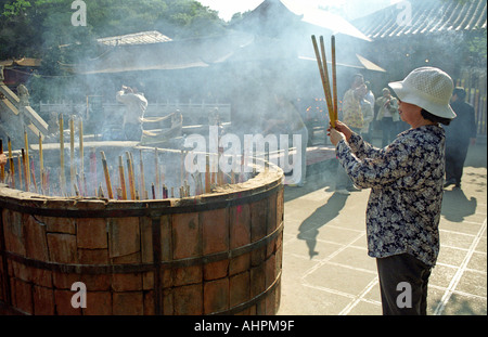 Femme Asiatique en priant avec josticks dans un temple à Kunming, Province du Yunan Chine Asie Banque D'Images