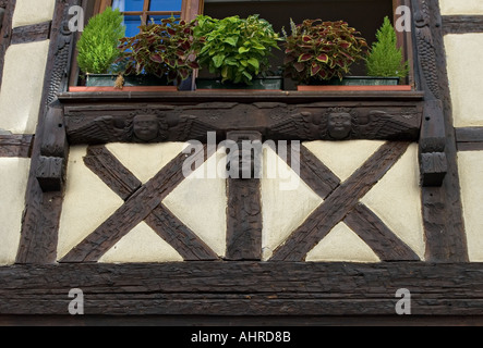 Détail des sculptures en bois de décoration autour d'un vieux châssis de fenêtre sur un édifice à colombages en Alsace Banque D'Images