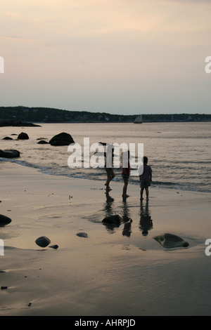 Trois enfants de Massachusetts Rockport 5, 7 et 8, jouant sur la plage au coucher du soleil, surtout sihouetted. Banque D'Images