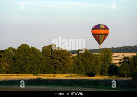 Un ballon à air chaud le soir à propos de la lumière du soleil à la terre près de la ville de Cotswold, Chipping Campden Gloucestershire Banque D'Images