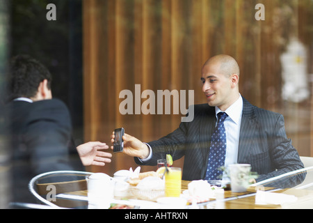 Deux hommes d'affaires dans un restaurant à un téléphone cellulaire Banque D'Images
