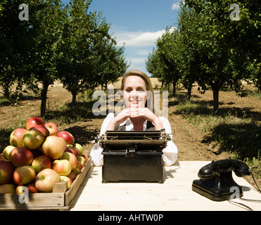 Femme assise au bureau en verger. Banque D'Images