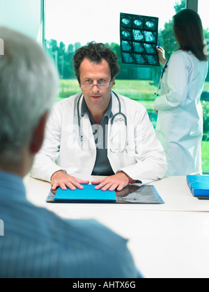 Deux médecins discutant des rayons x à des patients d'âge mûr. Banque D'Images