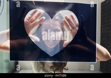 Jeune femme vue à travers ce graphique en forme de coeur. Banque D'Images