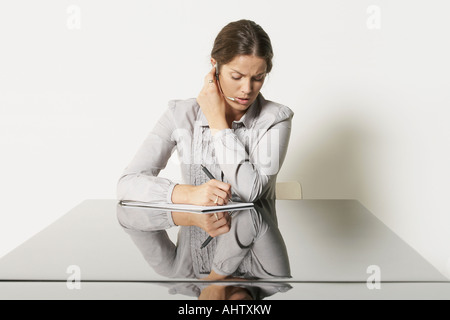 Jeune femme d'affaires au bureau avec des réflexions. Banque D'Images