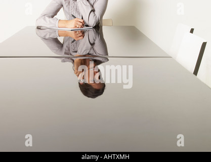 Jeune femme d'affaires au bureau avec des réflexions. Banque D'Images