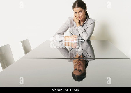 Jeune femme d'affaires au bureau avec des réflexions. Banque D'Images