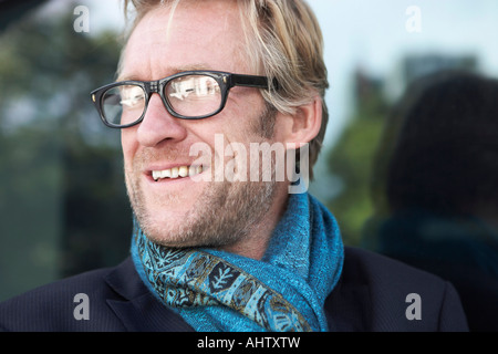 Businessman wearing scarf extravagantes appuyé contre la fenêtre avec lunettes. Banque D'Images