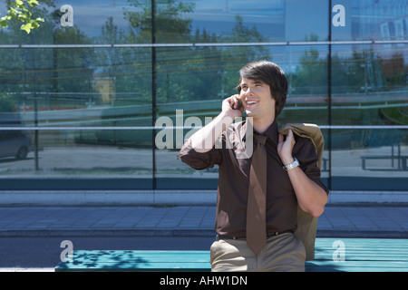 Businessman se pencha sur la table en face de l'office sur le mobile en souriant. Banque D'Images