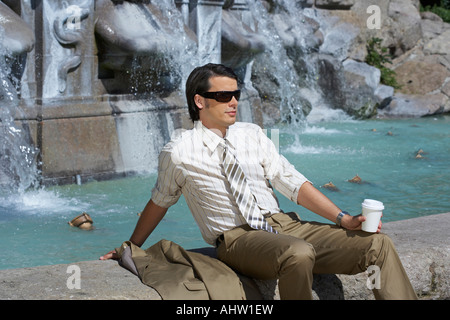 Portrait par fontaine avec du café pour aller porter des lunettes Banque D'Images