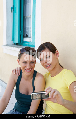 Deux jeunes filles à l'extérieur d'une maison grecque prendre un autoportrait avec mobile smiling Banque D'Images