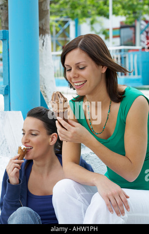 Deux smiling women sitting on steps en mangeant de la crème glacée. Banque D'Images