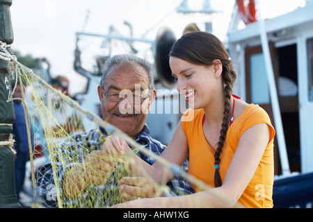 Jeune fille et un filet de pêche pêcheur sur l'ensemble de couture petit port en arrière-plan. Banque D'Images