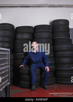 Mécanicien assis sur une pile de pneus Banque D'Images