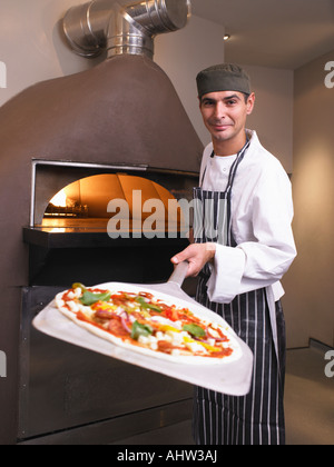 Pizza chef holding pizza en face de four Banque D'Images