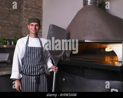 Pizza chef holding de la pagaie dans l'avant du four Banque D'Images