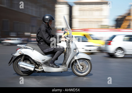 Rider sur le trafic passé les vitesses scooter dans le cadre de la Piazza Venezia au centre-ville de Rome Lazio Italie Banque D'Images