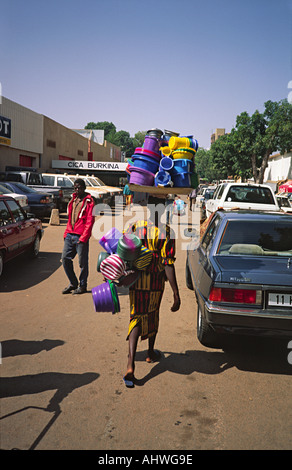Une vendeuse de rue marchant avec des articles de cuisine en plastique sur sa tête. Ouagadougou, Burkina Faso Banque D'Images
