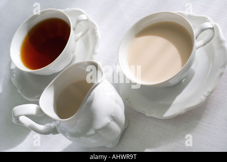 Deux tasses de thé avec du lait et un pot à lait en porcelaine sur la nappe blanche à Shallow DOF sur le bord de la tasse de la droite. Banque D'Images