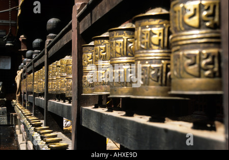 Rangée de roues à prières bouddhistes en laiton au Temple d'Or à Patan, dans la vallée de Katmandou, au Népal. Artefacts religieux traditionnels dans un temple sacré. Banque D'Images