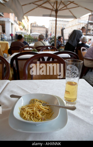 À moitié mangé bol de Spaghetti Carbonara et verre de bière assis sur une table dans un café de la rue de la Piazza Navona Banque D'Images