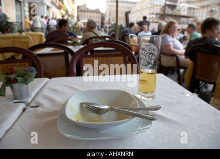 Complètement mangé bol de Spaghetti Carbonara et demi verre de bière assis sur une table dans un café de la rue de la Piazza Navona Banque D'Images