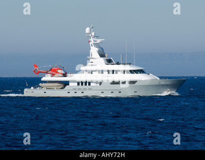 Un grand yacht de croisière avec un hélicoptère rouge sur son pont. (M/Y Triton 163 pieds de long) Banque D'Images