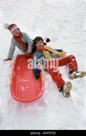 Retro 70s photo de deux frères de race blanche glissant sur hill en hiver Banque D'Images