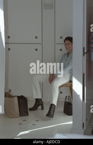 Femme assise sur un tabouret et rit alors qu'elle repose de shopping Banque D'Images