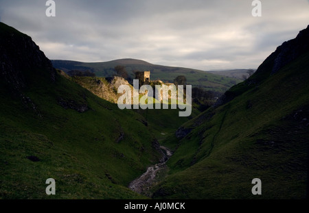 La lumière du soleil met en lumière le spectaculaire château de Peveril trônant fièrement sur un éperon rocheux au-dessus de la belle grotte Dale . Banque D'Images