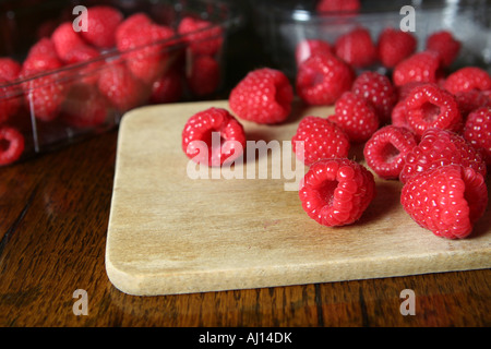 Studio shot de framboises sur planche en bois avec en plus dans des barquettes fond sombre Banque D'Images